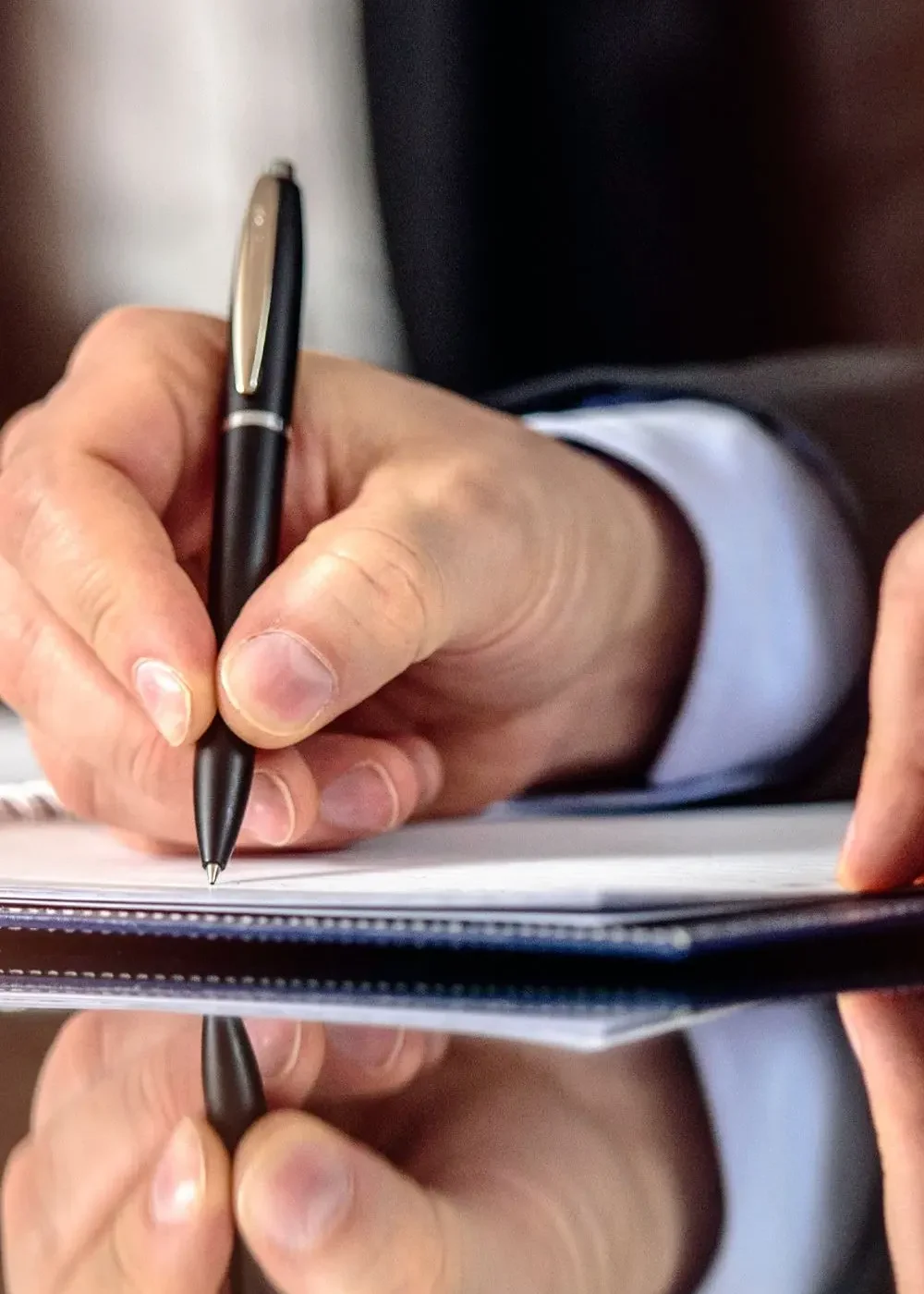 Close-up of an HR professional's hands reviewing and organizing important HR documents on a desk.